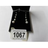 A pair of white gold and graduated pearl drop earrings.