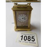 A brass cased miniature carriage clock with porcelain panels.
