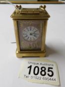 A brass cased miniature carriage clock with porcelain panels.