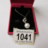 A white gold diamond and pearl pendant necklace.