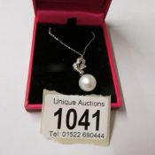 A white gold diamond and pearl pendant necklace.