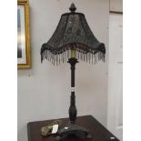 An ornate black table lamp with beaded shade