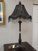 An ornate black table lamp with beaded shade