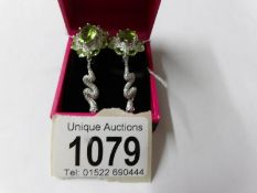 A pair of silver CZ and peridot earrings.