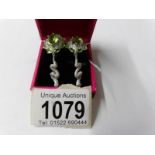 A pair of silver CZ and peridot earrings.