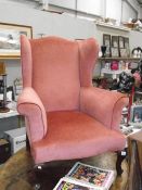 A pink wing arm chair on Queen Anne style legs.