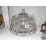 A large heavy clear glass cake dome on foot