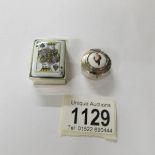 A silver snuff box with King of spades card to top and a silver pill box with lady.