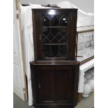 A dark oak corner cupboard with leaded glass door.