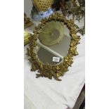 An oval mirror in metal vine leaf frame.