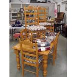 A light oak dining table with 6 chairs (2 chairs missing turnings from back).