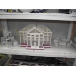 A dolls house consrevatory with fancy painted white metal garden furniture