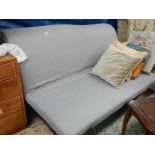 A futon with dark blue cover and cushions.