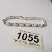 A silver opal and ruby line bracelet.