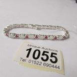 A silver opal and ruby line bracelet.