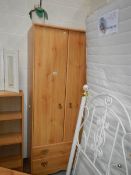 A pine effect 2 door, 2 drawer wardrobe.