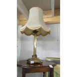A brass Corinthian column table lamp with shade.