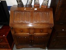 An oak bureau with carved drop front.