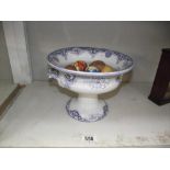 A raised blue and white pottery bowl containing a collection of pottery and wooden eggs.