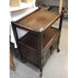 A 1930's dark oak tea trolley with carved cupboard door to base (collect only).