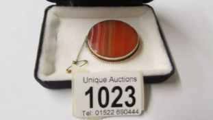 A 9ct gold Scottish brooch in banded agate with safety chain.