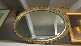 An oval gilt framed mirror.