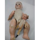 A porcelain headed doll and a smaller example with wooden parts.