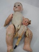 A porcelain headed doll and a smaller example with wooden parts.
