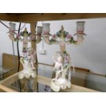 A pair of continental porcelain candelabra surmounted cherubs.