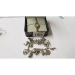A silver marcasite ladies wristwatch and an old charm bracelet with 15 mainly silver charms.
