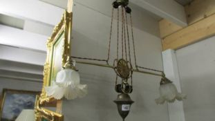 An Edwardian brass electrolier doubel rise and fall ceiling light with shades.