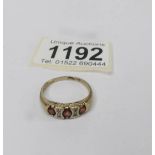 A 3 stone yellow gold garnet ring with diamonds.