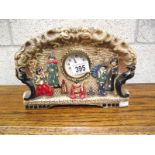 A plaster mantel clock featuring an oriental scene, marked too rear 'Emboss ware'.