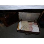 A vintage case containing various household textiles and linens including napkins,