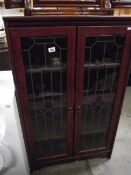 A dark wood stained display cabinet with leaded glass doors.