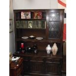 A dark oak dresser with leaded glass door and linen fold carved doors.