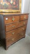 An oak 2 over 3 chest of drawers with brass handles.