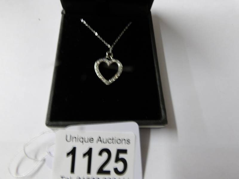 A white gold diamond set heart shaped pendant on gold chain.