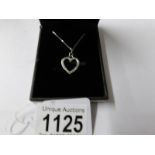 A white gold diamond set heart shaped pendant on gold chain.