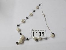 A freshwater pearl necklace with onyx spacers set in silver.