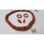A coral necklace and 2 pairs of coral earrings.