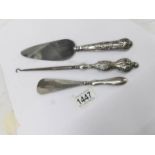 A silver handled cake slice, button hook and shoe horn.