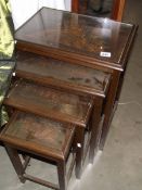 A set of 4 nesting tables with carved tops.