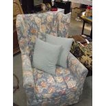 A wing arm chair with floral patterned covers.
