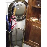 A large circular brass framed mirror, umbrella stand with content and fire screen.