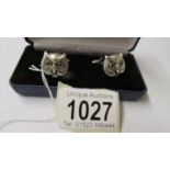 A pair of silver owl cuff links with glass eyes.