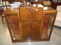 An art deco oak drinks cabinet with glazed side cabinets.