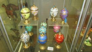 11 musical porcelain and gilt eggs on stands. 1 a/f.