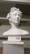 A plaster bust of a woman, nose chipped.