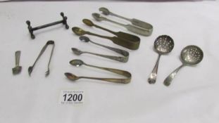 A mixed lot including sugar tongs, sifter spoons etc.